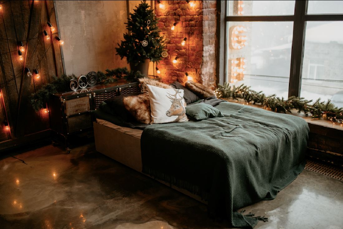 Cozy bedroom with string lights, Christmas tree and garland by a window