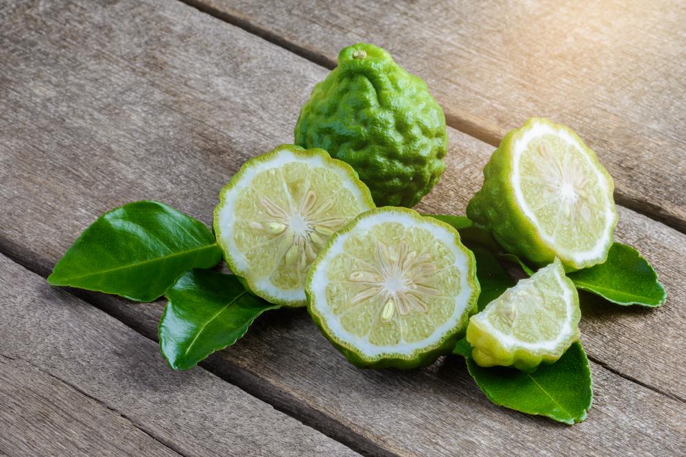 Halved bergamot citrus fruit showing pale interior among green leaves
