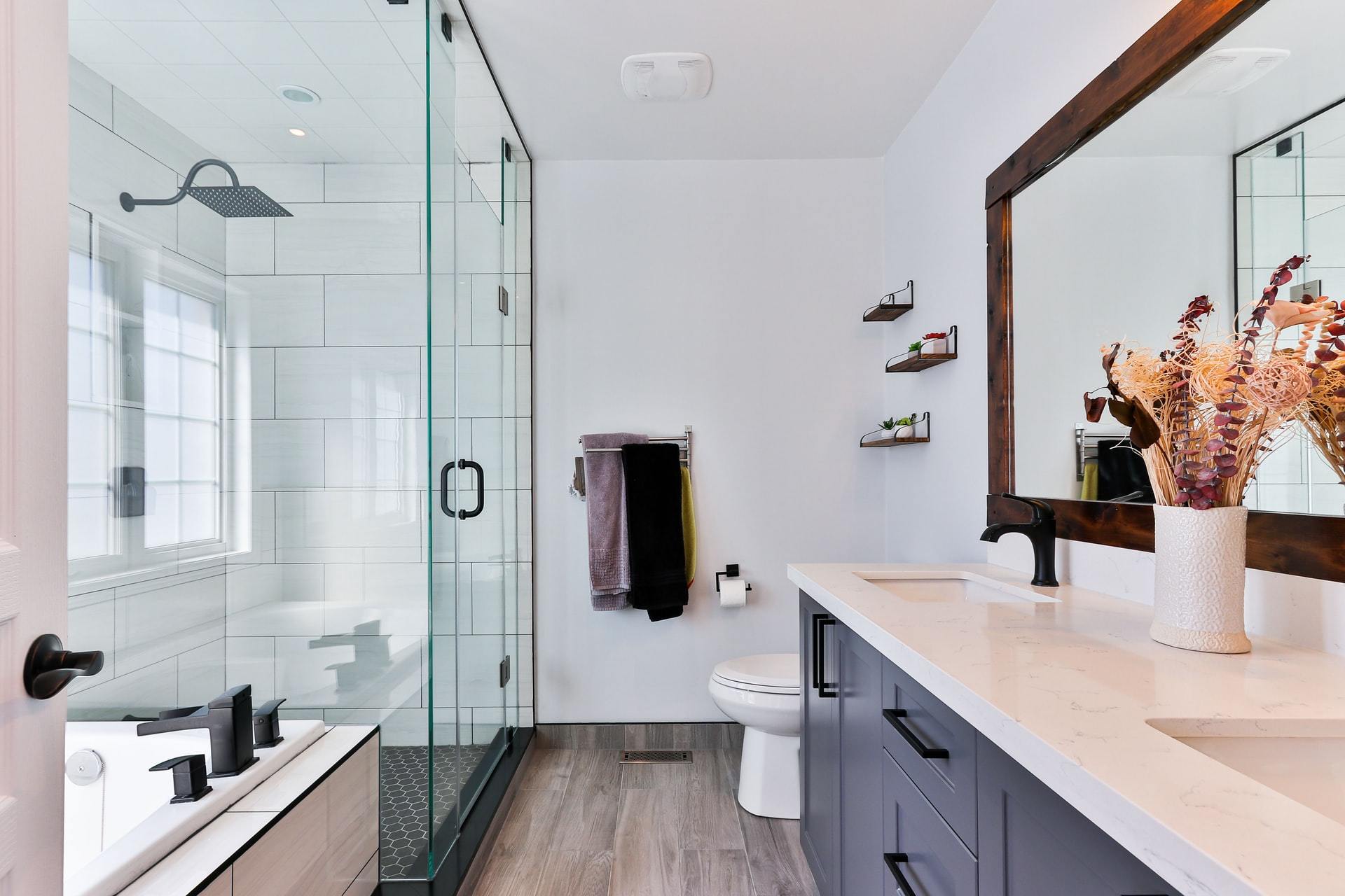 Bright modern bathroom with glass shower, vanity mirror and dried pampas grass