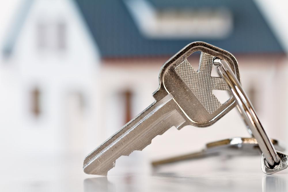 House keys in front of a blurred home for sale