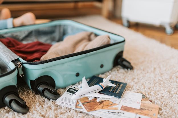 Open packed suitcase with travel documents and a toy airplanean You Bring Candles on a Plane?